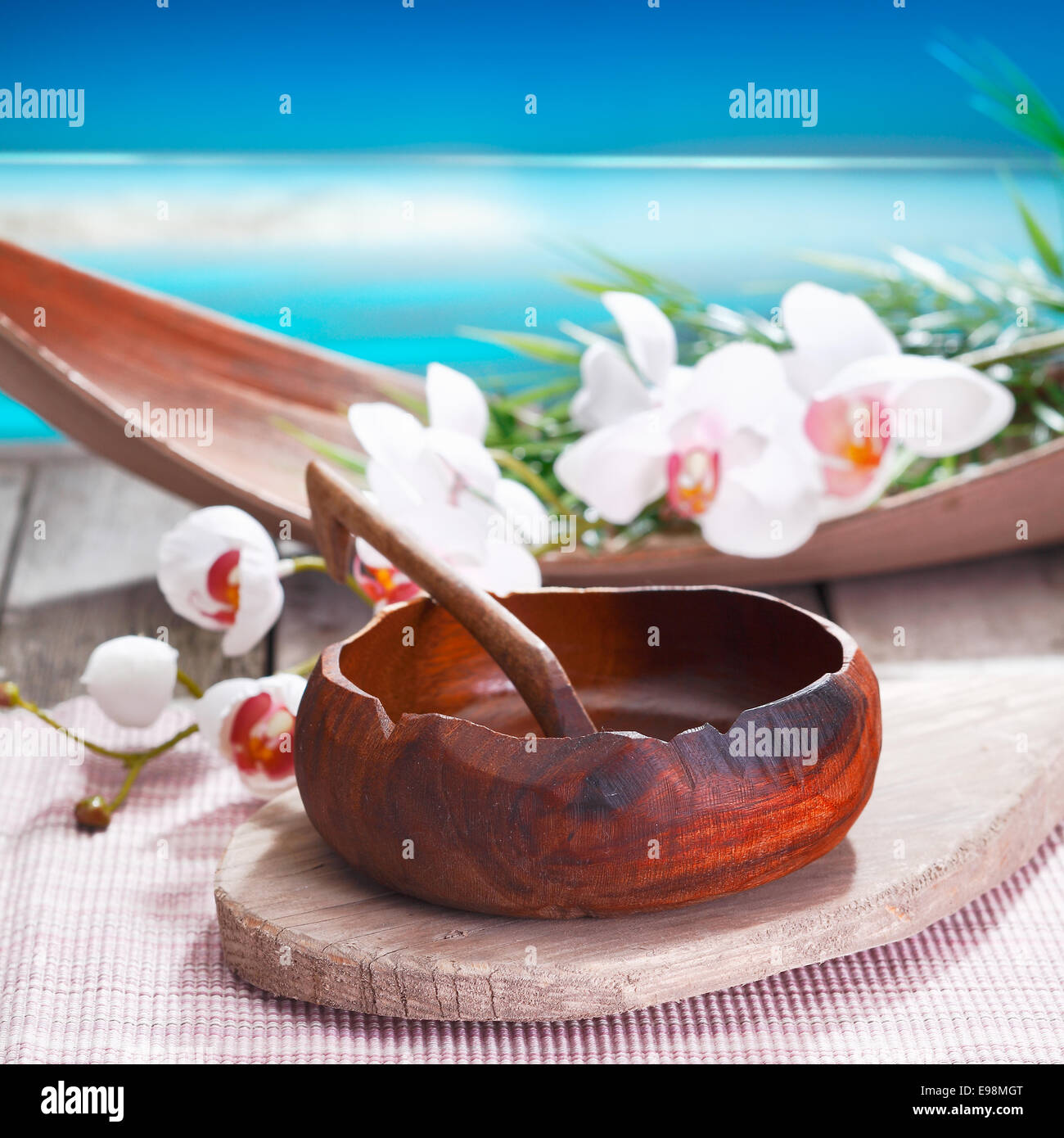 Esotiche orchidee bianche e un etnica ciotola artigianale conferiscono un'aria differente per questo trattamento spa a fianco l'acqua Foto Stock