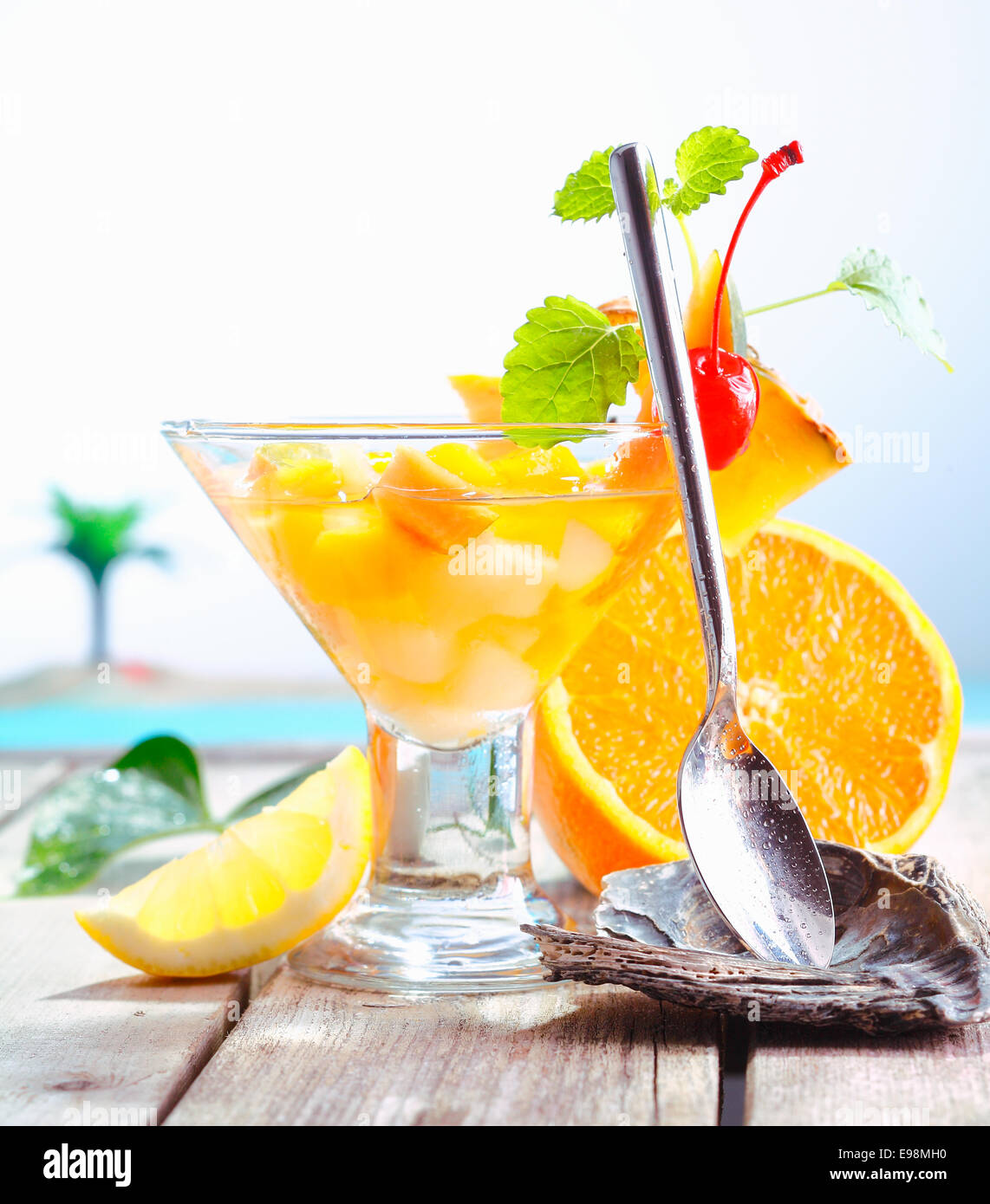 Colorati frutti esotici cocktail di fresca frutta tropicale presentato con un cucchiaio in una posizione di riposo in corrispondenza di una sistemazione di resort Foto Stock