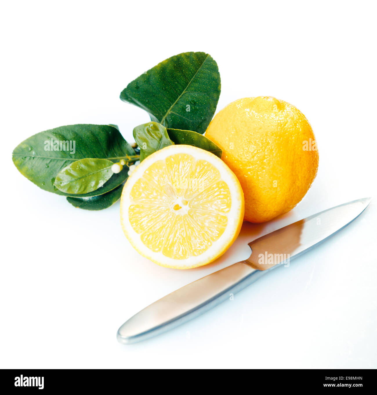 Dimezzato e intera di limoni freschi con foglie e un coltello su un bianco di sfondo per studio Foto Stock