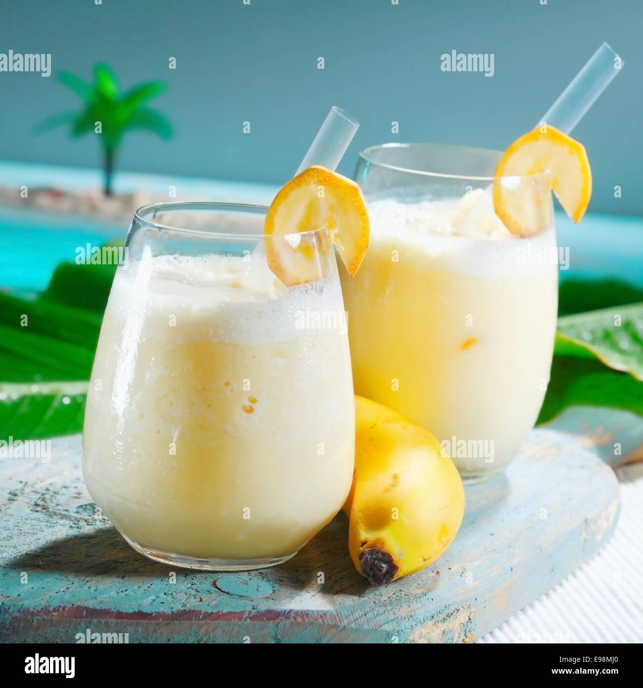 Primo piano di due bicchieri di fruttato sano frullato di banana mescolate con yogurt servito presso un lungomare resort tropicale Foto Stock