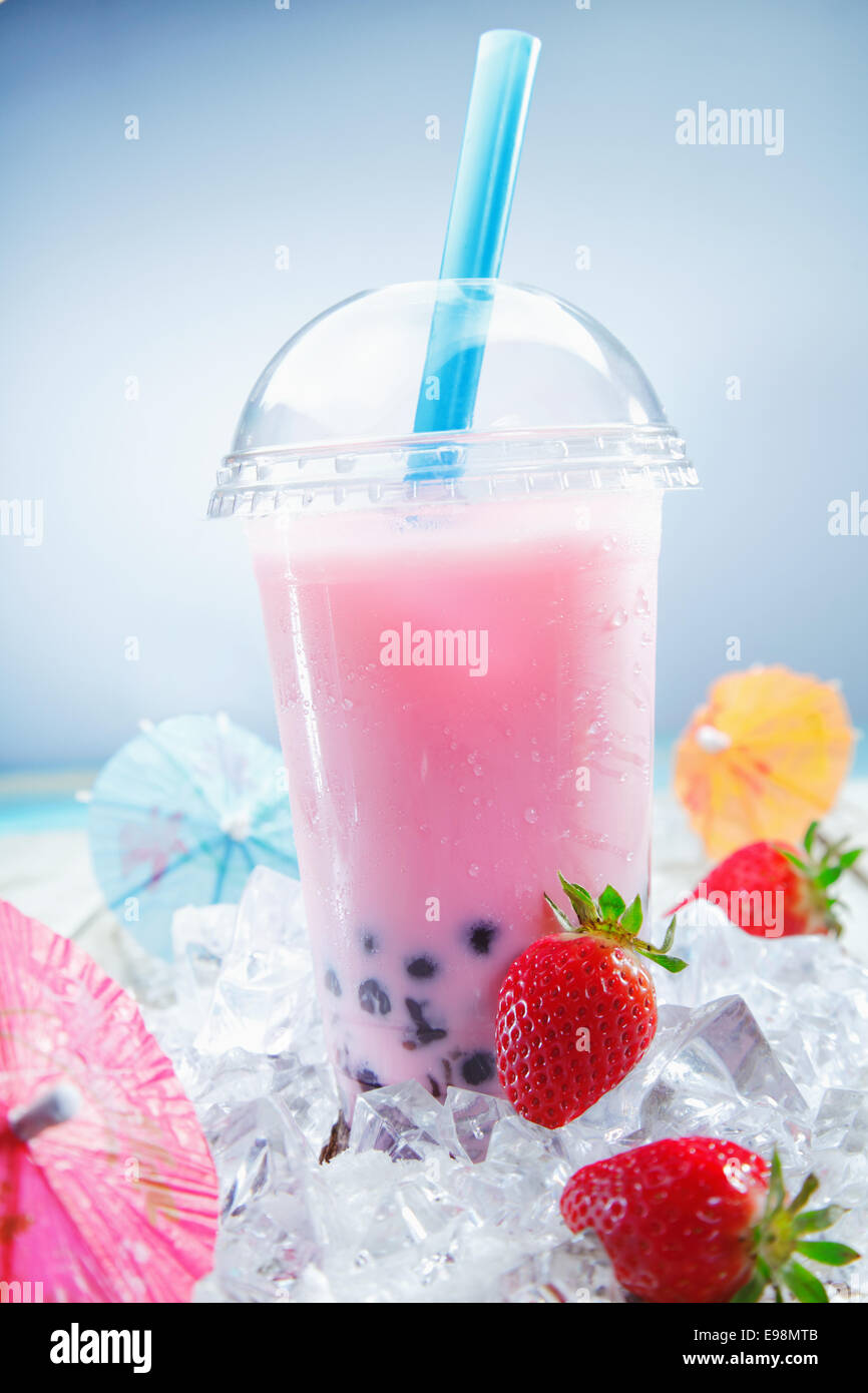 Fruttato Boba Fragola tè bolla sul ghiaccio tritato, in piedi su un ponte vicino alla spiaggia Foto Stock
