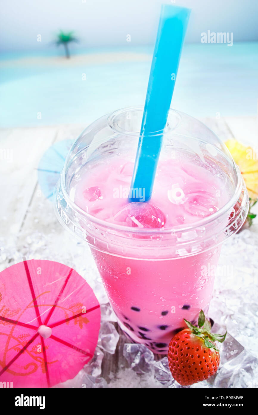 Deliziosa miscelate bolle di fragola tè con bacche servita con un cocktail di rosa parasol su una terrazza che si affaccia sull'oceano Foto Stock