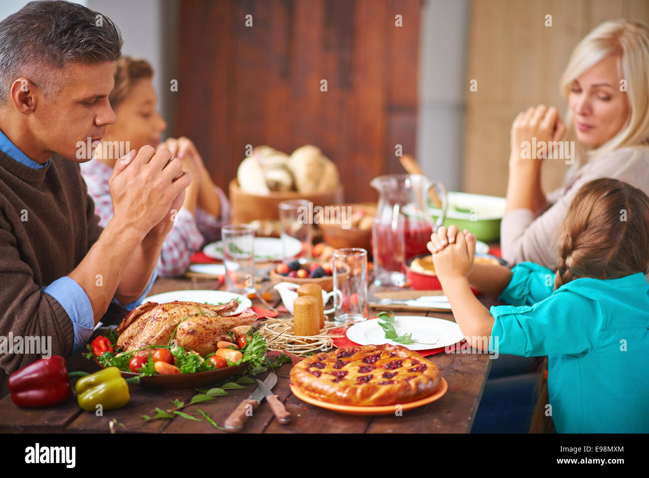 Ritratto di famiglia moderna di quattro seduti al tavolo di festa e di preghiera Foto Stock