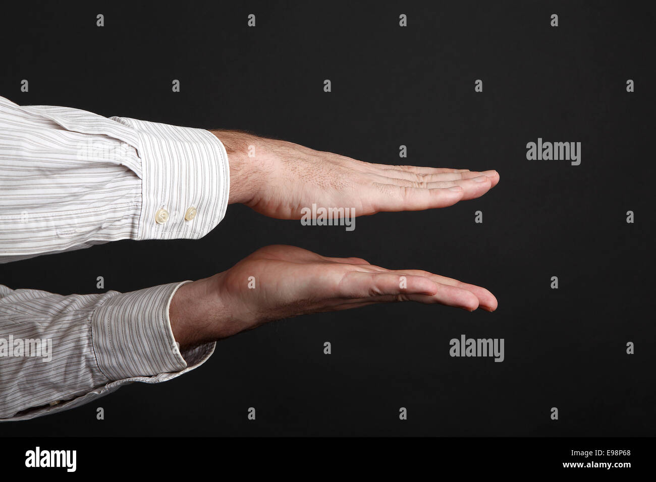 Maschio caucasico mani spremere qualcosa davanti a uno sfondo nero Foto Stock