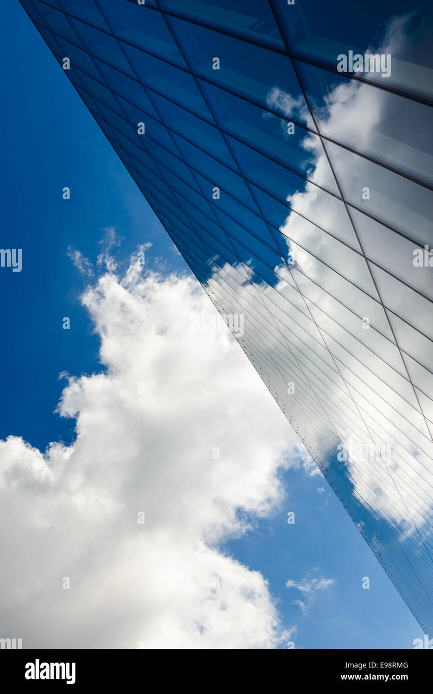 Le nuvole in un cielo blu riflesso contro una parete di vetro Foto Stock