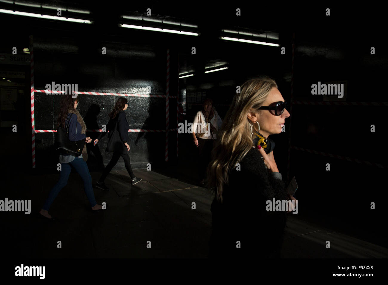 Persone uscire da una stazione della metropolitana in autunno luce della sera, creando un forte contrasto tra luce e ombra, buie e luminose. Londra. Foto Stock