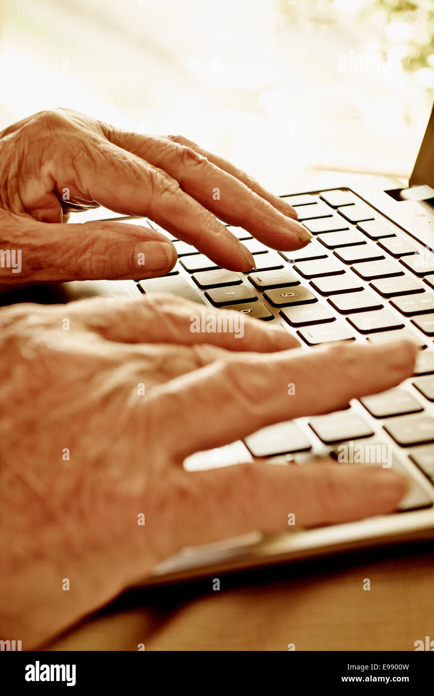 Senior persona con le mani in mano utilizzando un computer portatile. Foto Stock