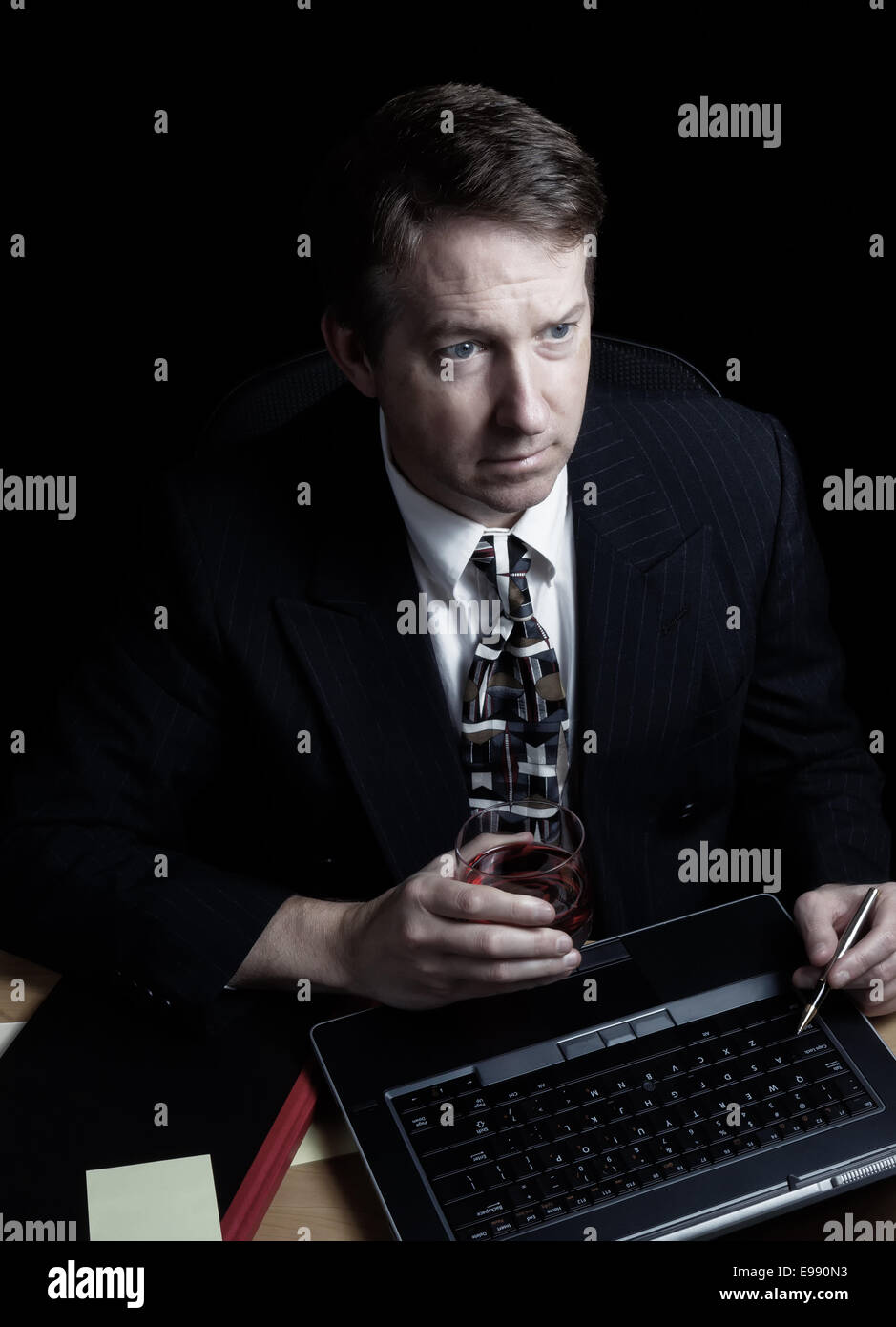 L'immagine verticale dell uomo d affari e guardando lo schermo del computer, lavora fino a tardi con sfondo nero Foto Stock