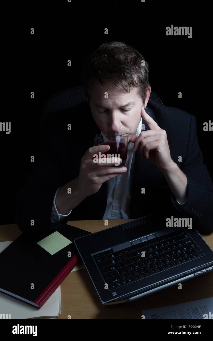 L'immagine verticale dell uomo d affari e bere alcool, lavora fino a tardi con sfondo nero Foto Stock