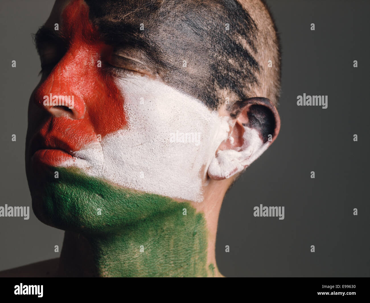 L'uomo con il suo volto dipinto con la bandiera palestinese. L'uomo gli occhi chiusi e cercando di traverso. Foto Stock