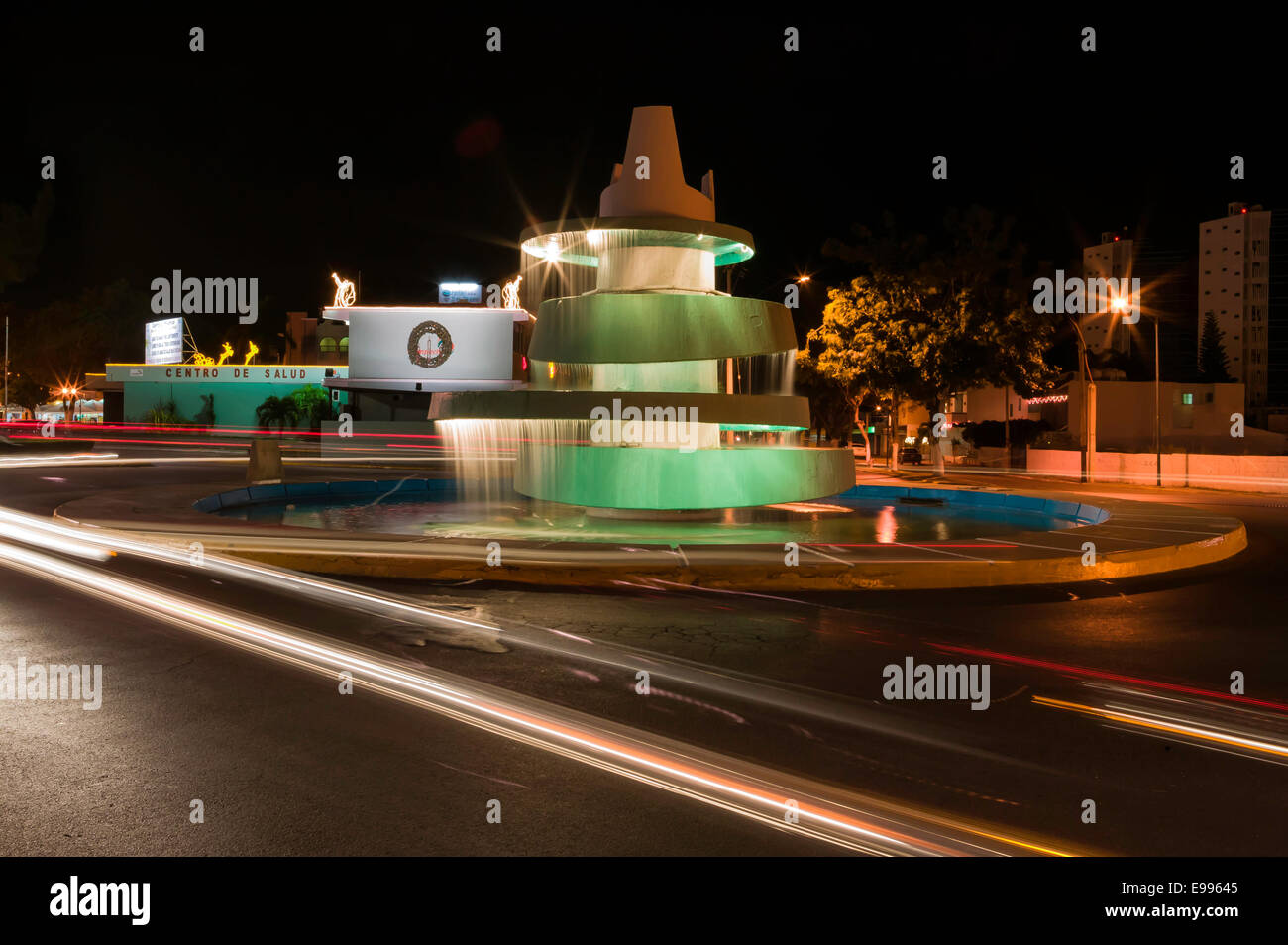 Tempo di esposizione dei sentieri di luce dell'automobile passando una fontana in Campeche Messico di notte. Foto Stock