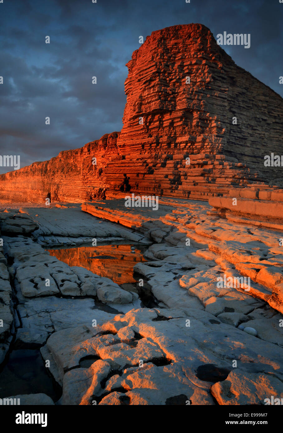 In tarda serata la luce del sole su scogliere a Nash punto, South Wales, drammaticamente girando la roccia di colore arancione / rosso Foto Stock