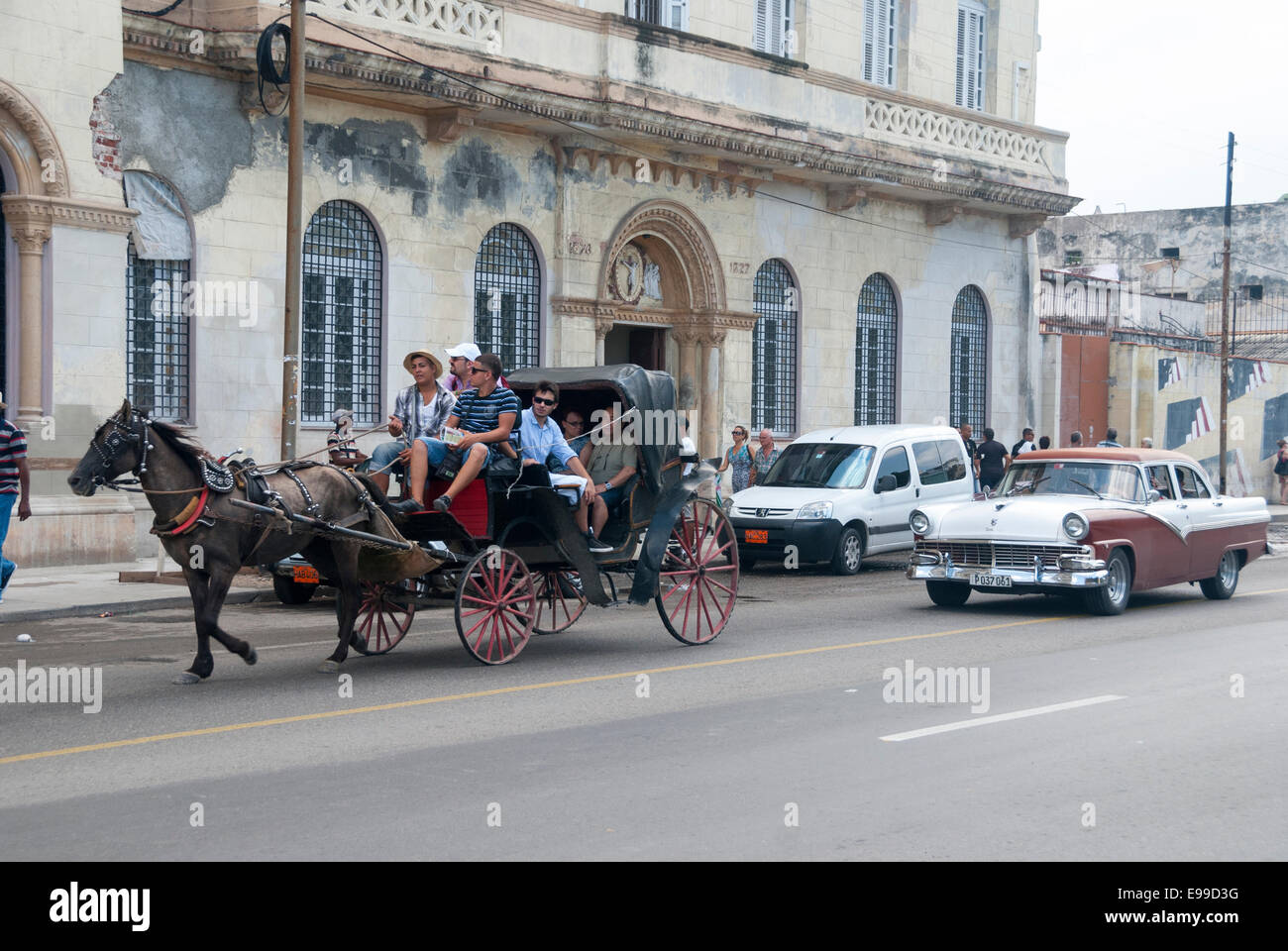 Un carro trainato da cavalli seguita da un vintage Ford Fairlane escort turisti sul famoso Malecon in Havana Cuba. Foto Stock