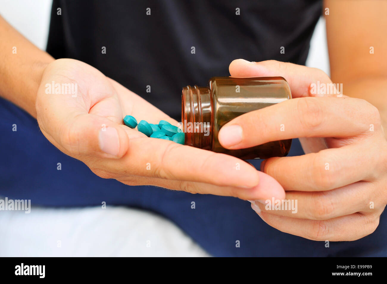 Un giovane con una bottiglia di pillole nelle sue mani Foto Stock