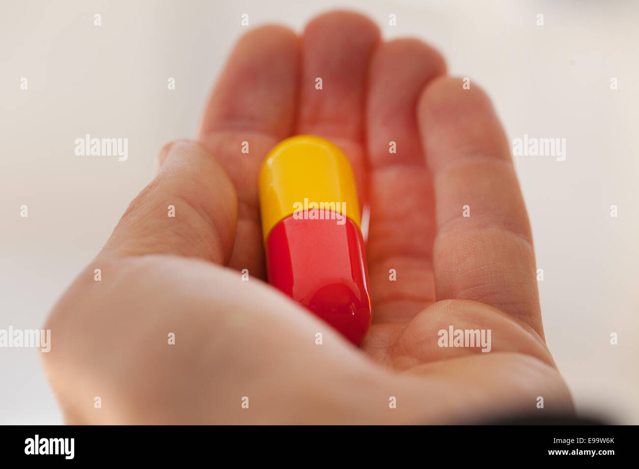 Inquadratura ravvicinata di una mano che tiene un rosso giallo capsule Foto Stock