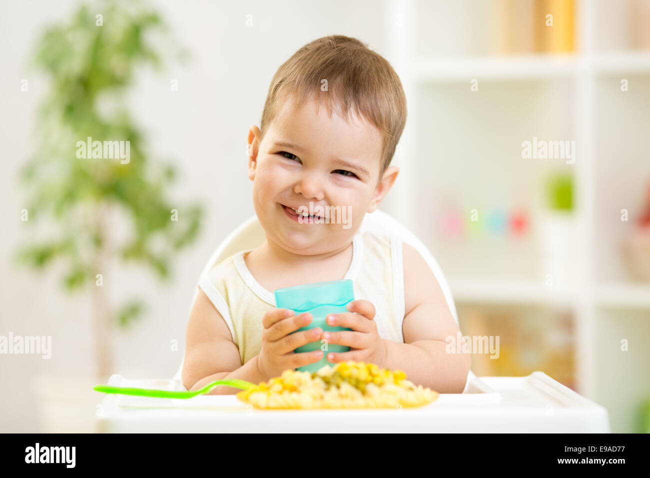 Sorridente kid boy mangiare al chiuso Foto Stock