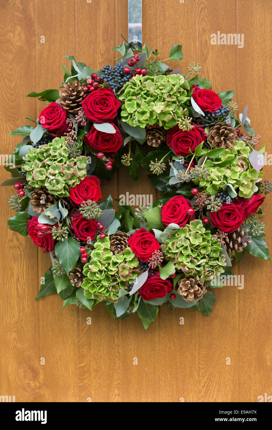 Rose rosse e foglie verdi ghirlanda di Natale appeso sulla moderna porta in  legno con letter box Foto stock - Alamy