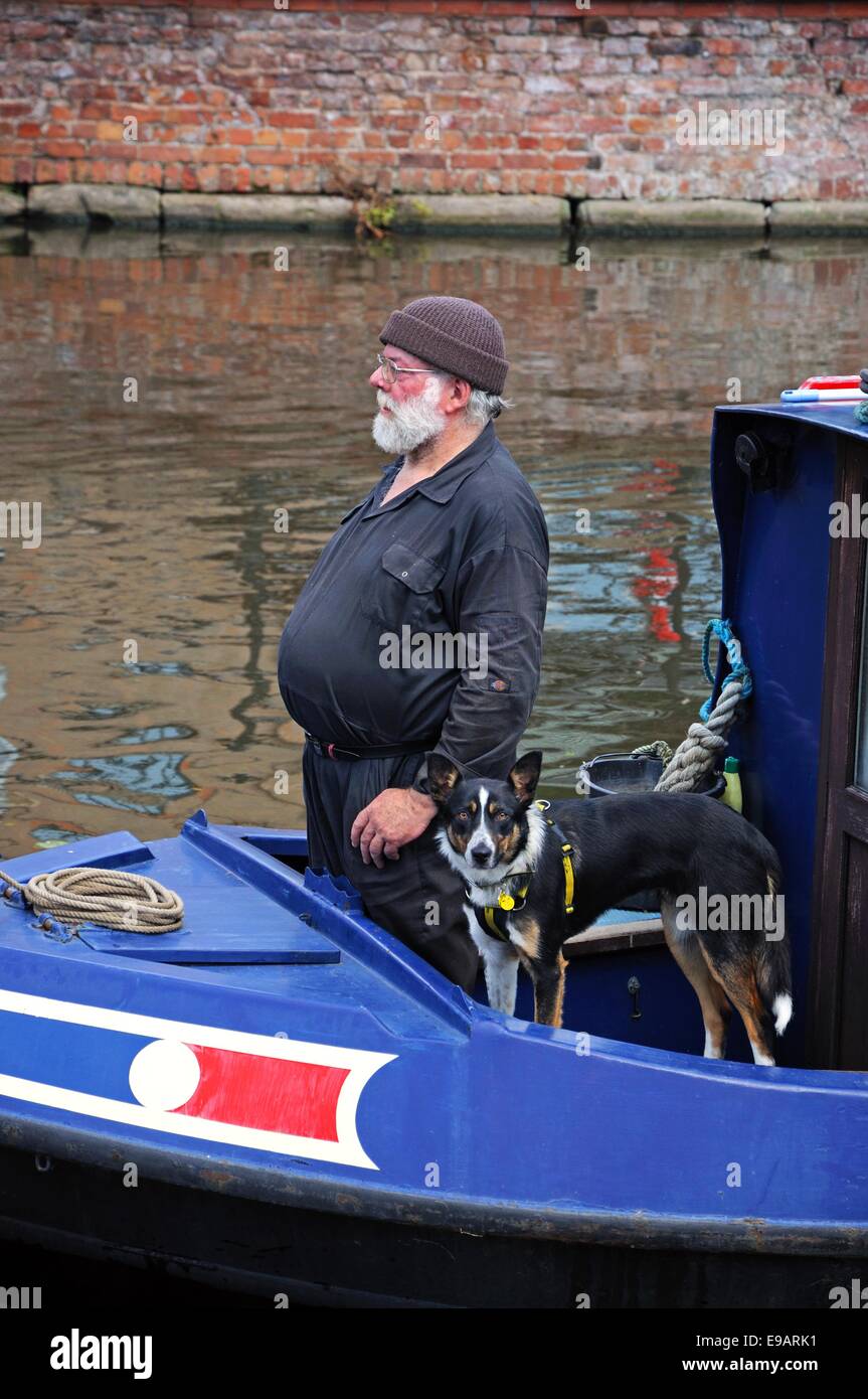 L uomo e il suo cane su un narrowboat lungo il Nottingham e Beeston Canal, Nottingham, Nottinghamshire, Inghilterra, Regno Unito, Europa occidentale Foto Stock