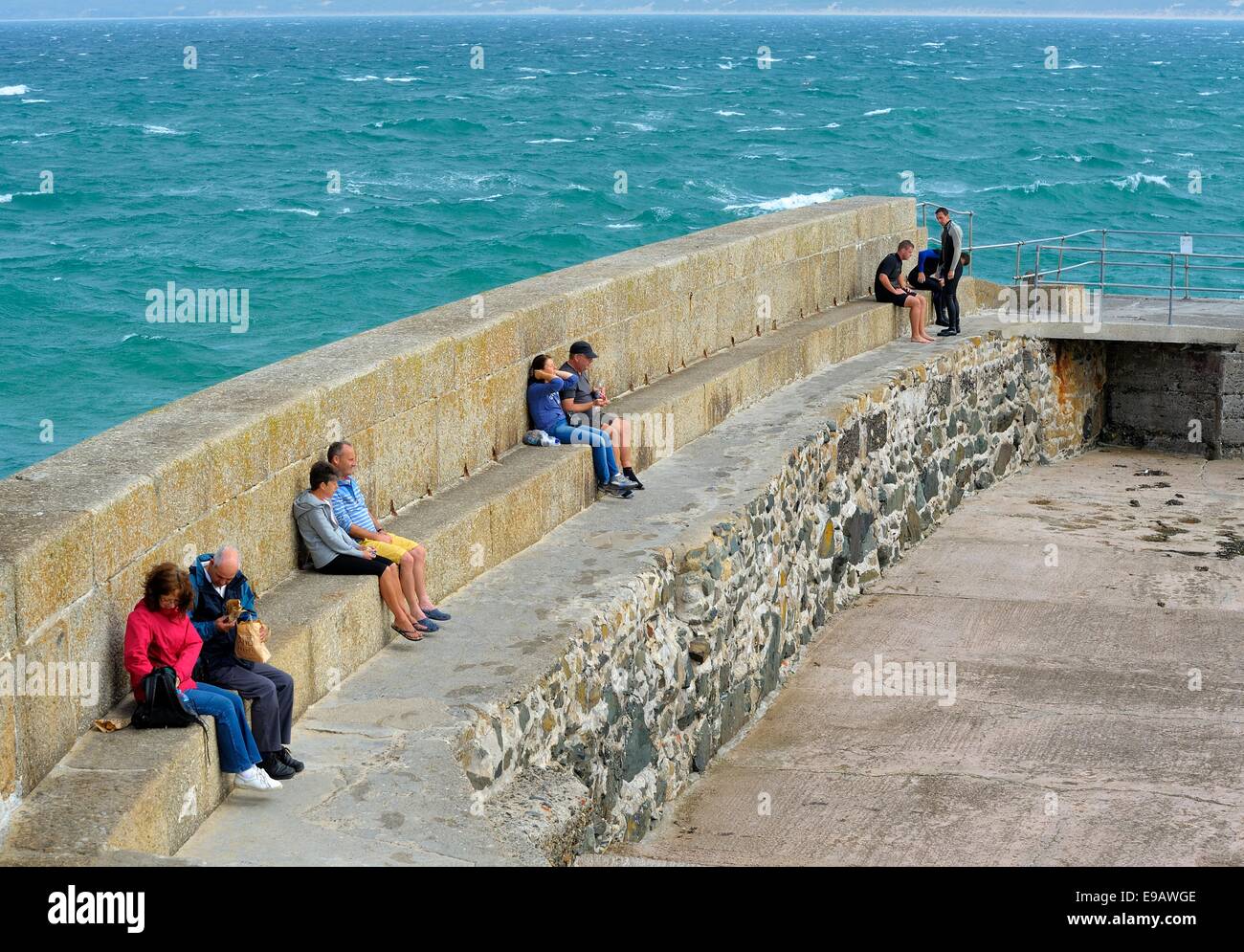 Persone mangiare e seduti sulle mura sul mare in St ives Cornwall Inghilterra Regno Unito Foto Stock