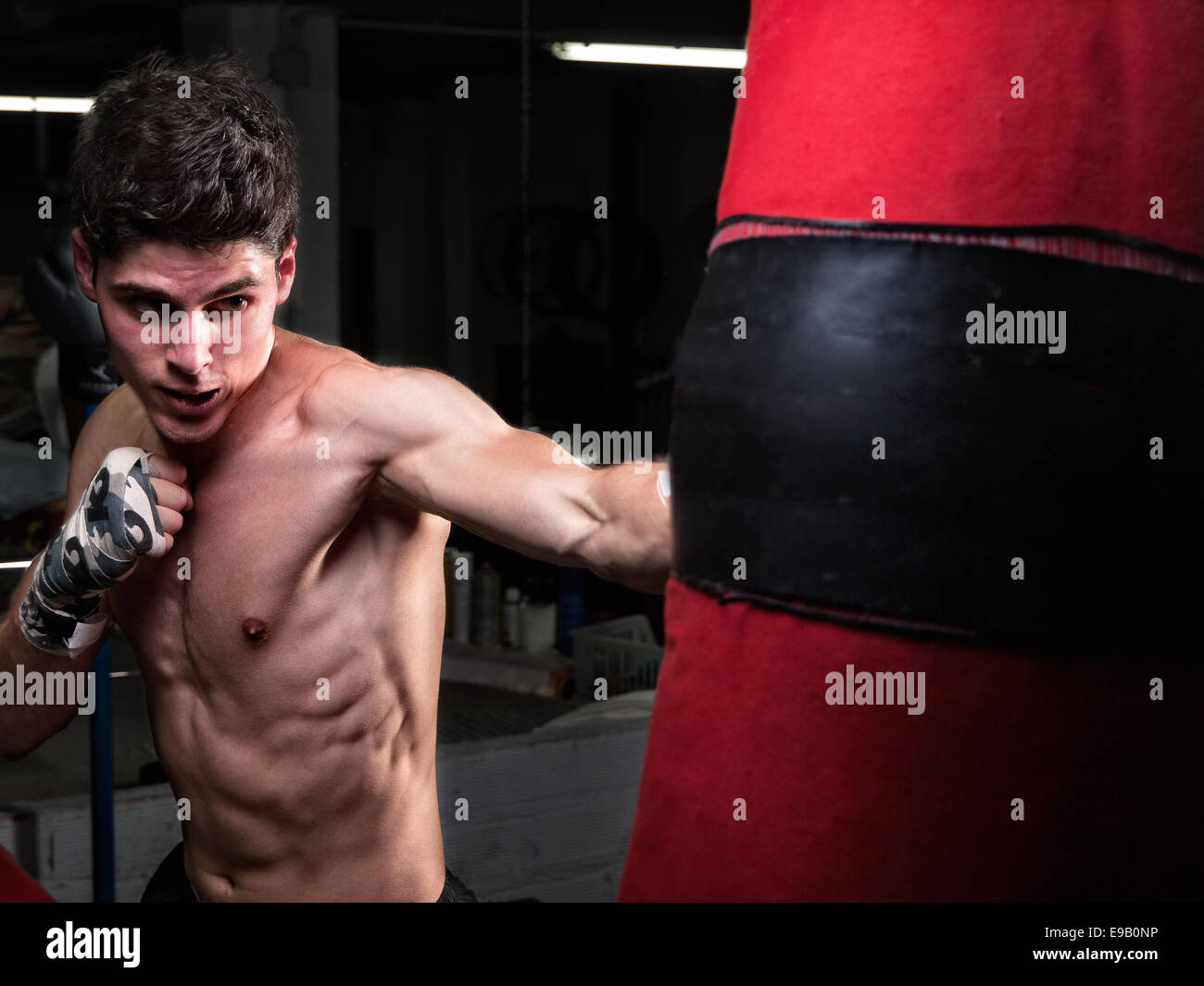 Giovani caucasici formazione Boxer con un sacco da boxe in casa sua palestra Foto Stock