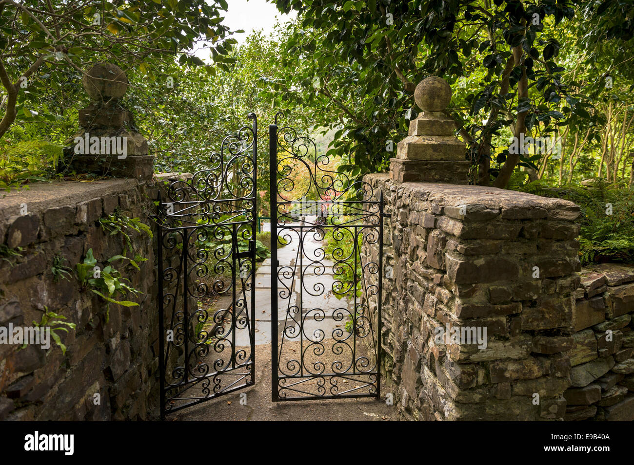 Una coppia di cancelli in ferro battuto, sfociante in un tipico inglese,  giardino paesaggistico Foto stock - Alamy