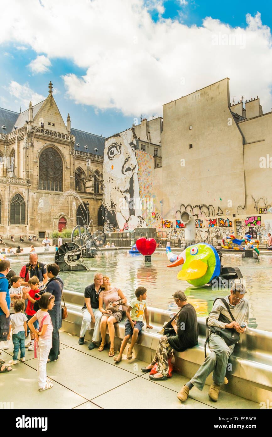 I turisti di prendere una pausa presso la Fontana Stravinsky vicino al centro Georges Pompidou, in background saint merry chiesa Foto Stock