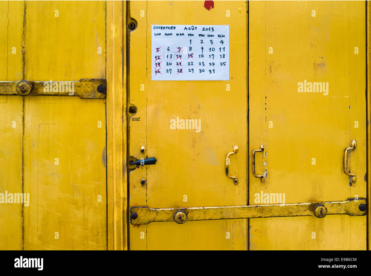 Avviso al giallo porta in legno di un negozio visualizza una calandra che mostra la tradizionale vacanza parigina il mese di agosto Foto Stock