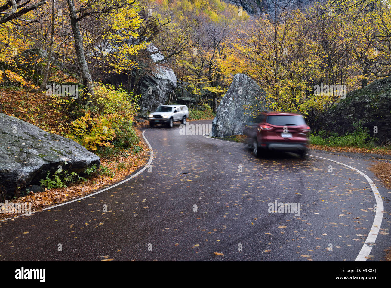 Macchine che passano sulla autostrada di avvolgimento 108 passano attraverso massi a contrabbandieri tacca stato parco vicino a Stowe Vermont USA con autunno fogliame degli alberi Foto Stock