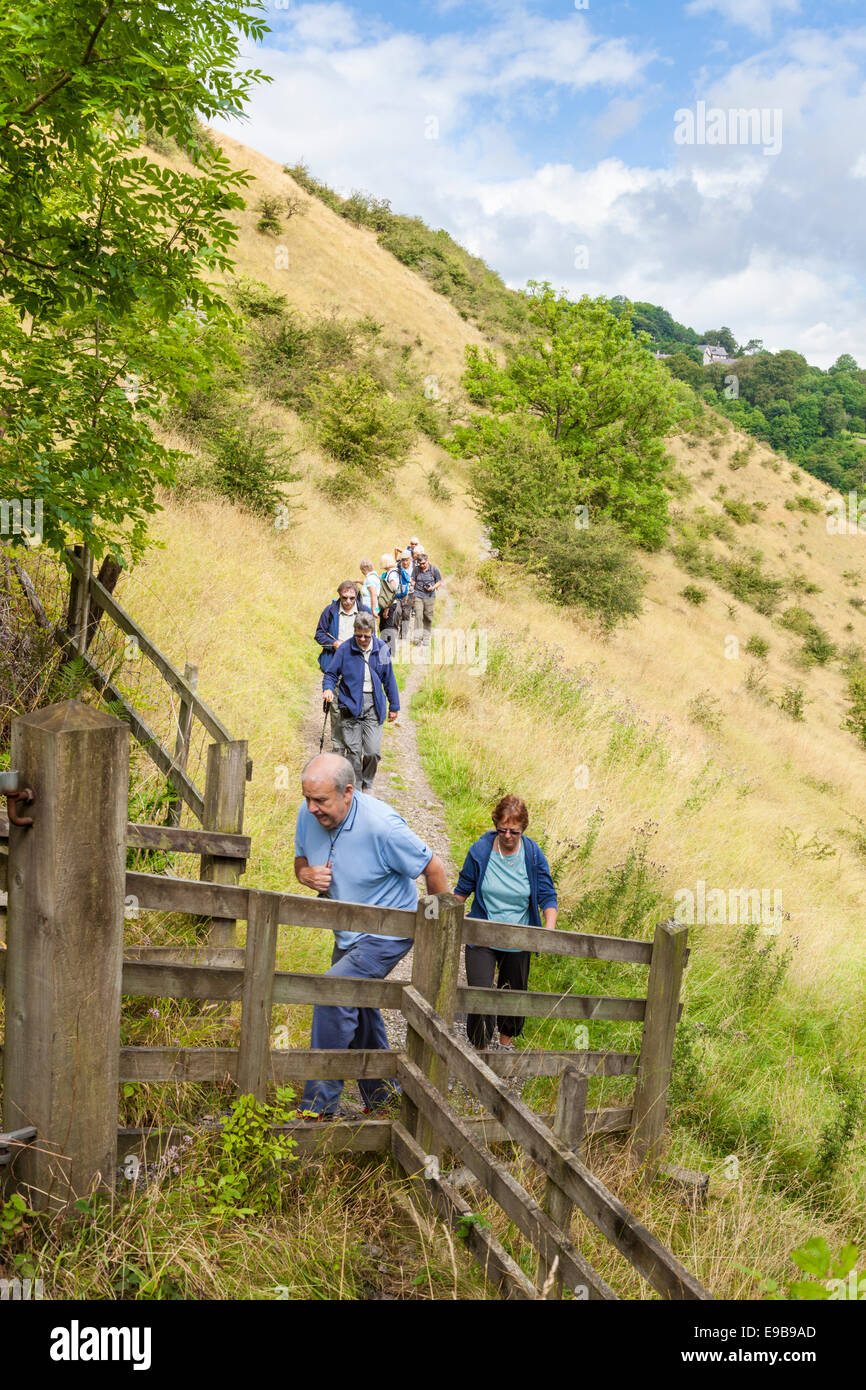 Un gruppo di anziani gli escursionisti a piedi su un percorso collinare a Upperdale, Derbyshire, picco bianco, Parco Nazionale di Peak District, England, Regno Unito Foto Stock