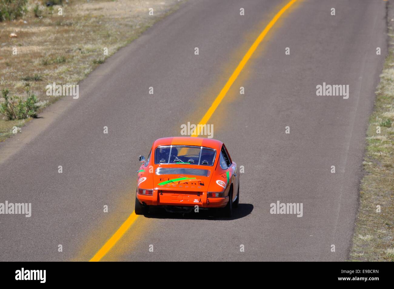 Vista posteriore di un arancione Porsche 911 racing car accelerando lungo una superstrada nella Carrera Panamericana road race in Messico Foto Stock