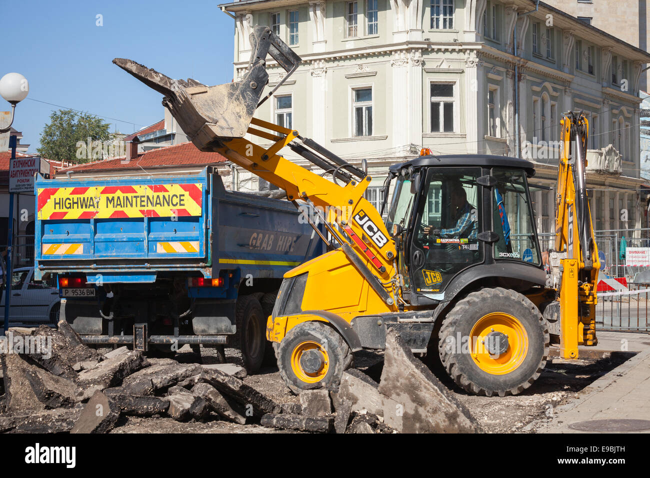 Ruse, Bulgaria - 29 Settembre 2014: lavori stradali. Autostrada manutenzione, uomo in giallo trattore rimuove il vecchio asfalto e loa Foto Stock