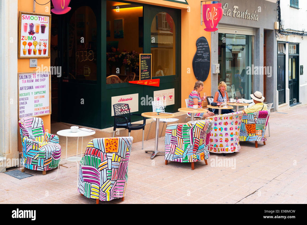 I turisti avente un rinfresco e seduto in un bar con tavoli esterni con sedie in una strada sul retro, Mahon, Menorca, Spagna Foto Stock