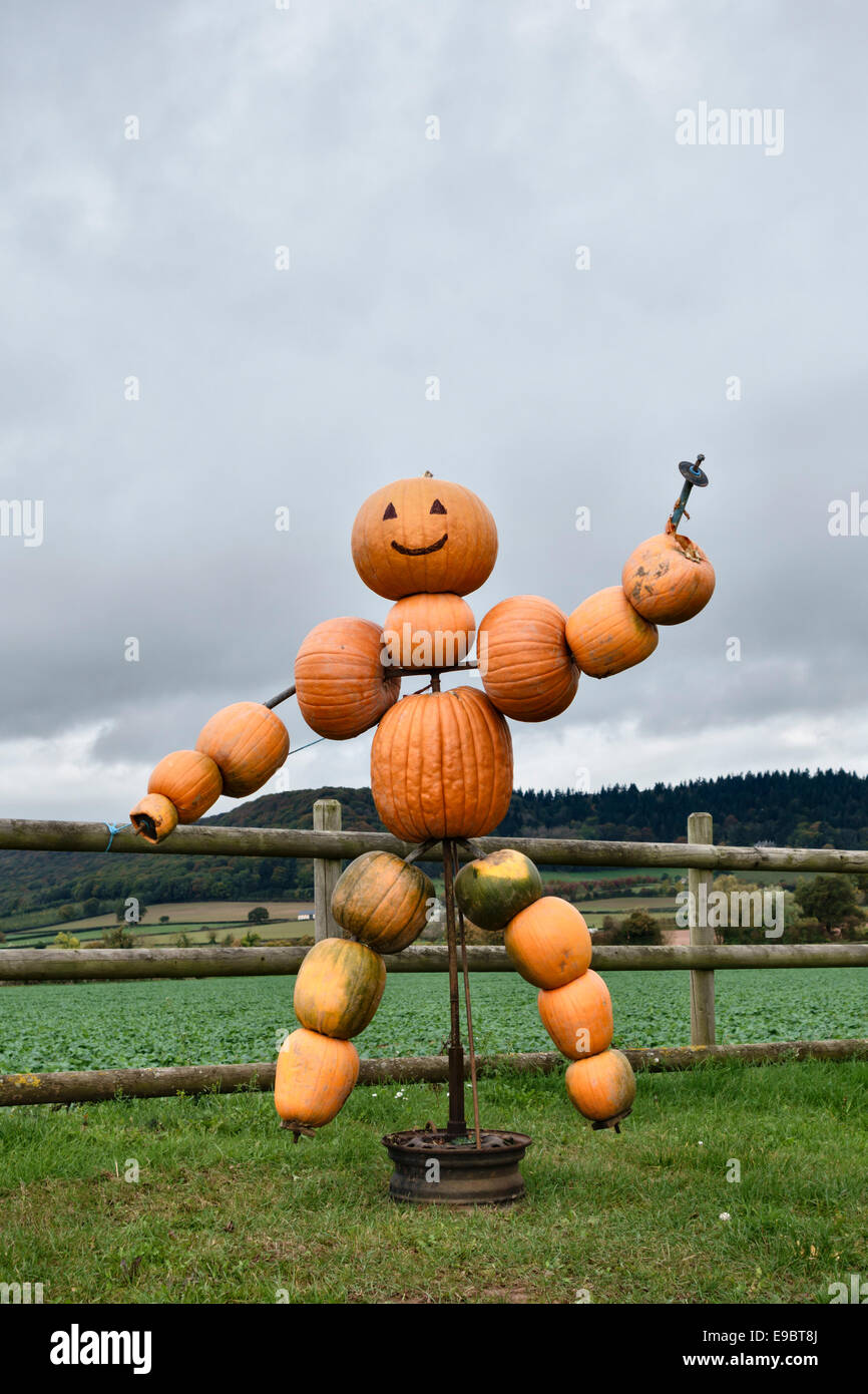 Una scultura fatta di zucche si trova in un cancello della fattoria che pubblicizza le zucche in vendita ad Halloween, vicino a Hereford, Regno Unito Foto Stock