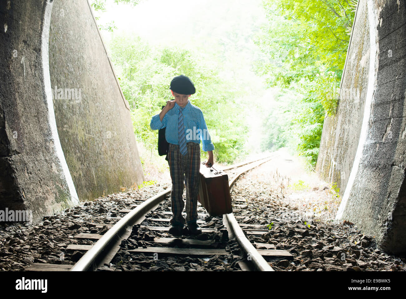 Bambino a camminare sulla strada ferrata con siutcase vintage. Foto Stock