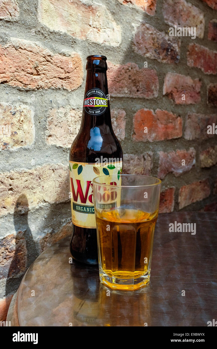 Una bottiglia di legno Wyld organici di sidro di mela di fronte a un muro di mattoni in una giornata di sole in estate. Verticale con spazio di copia Foto Stock