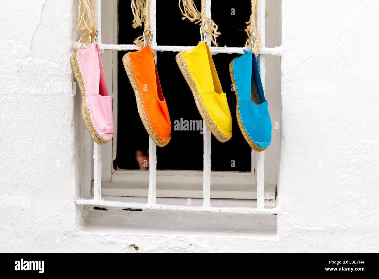 Quattro Colorati luminosamente tradizionali scarpe spagnolo appeso al di fuori di una finestra Foto Stock