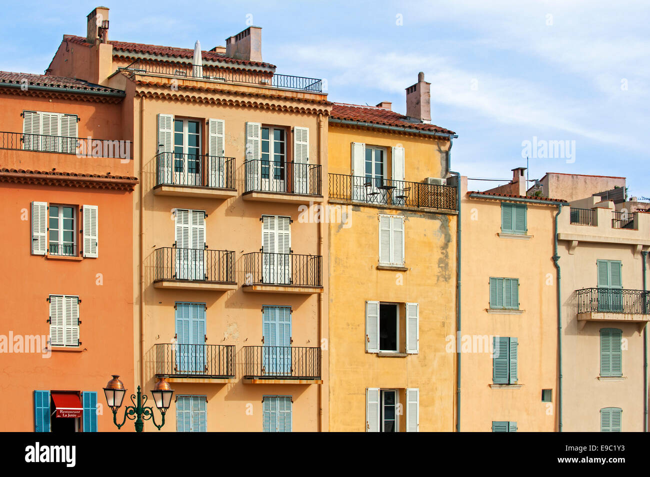 Balconi e finestre con tendine di case color pastello nella città Saint-Tropez lungo la Riviera Francese, Var, Francia Foto Stock