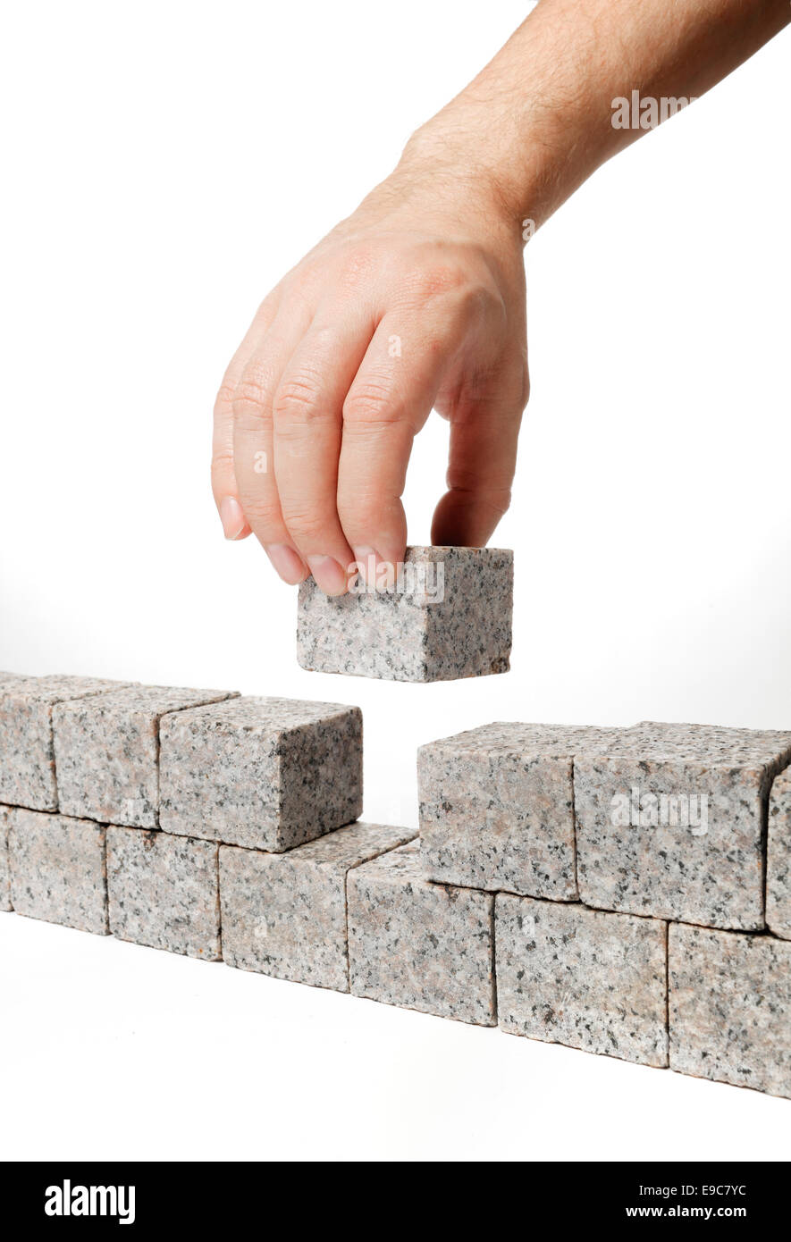L'uomo costruire un muro fatto di piccoli blocchi di roccia di granito. Foto Stock
