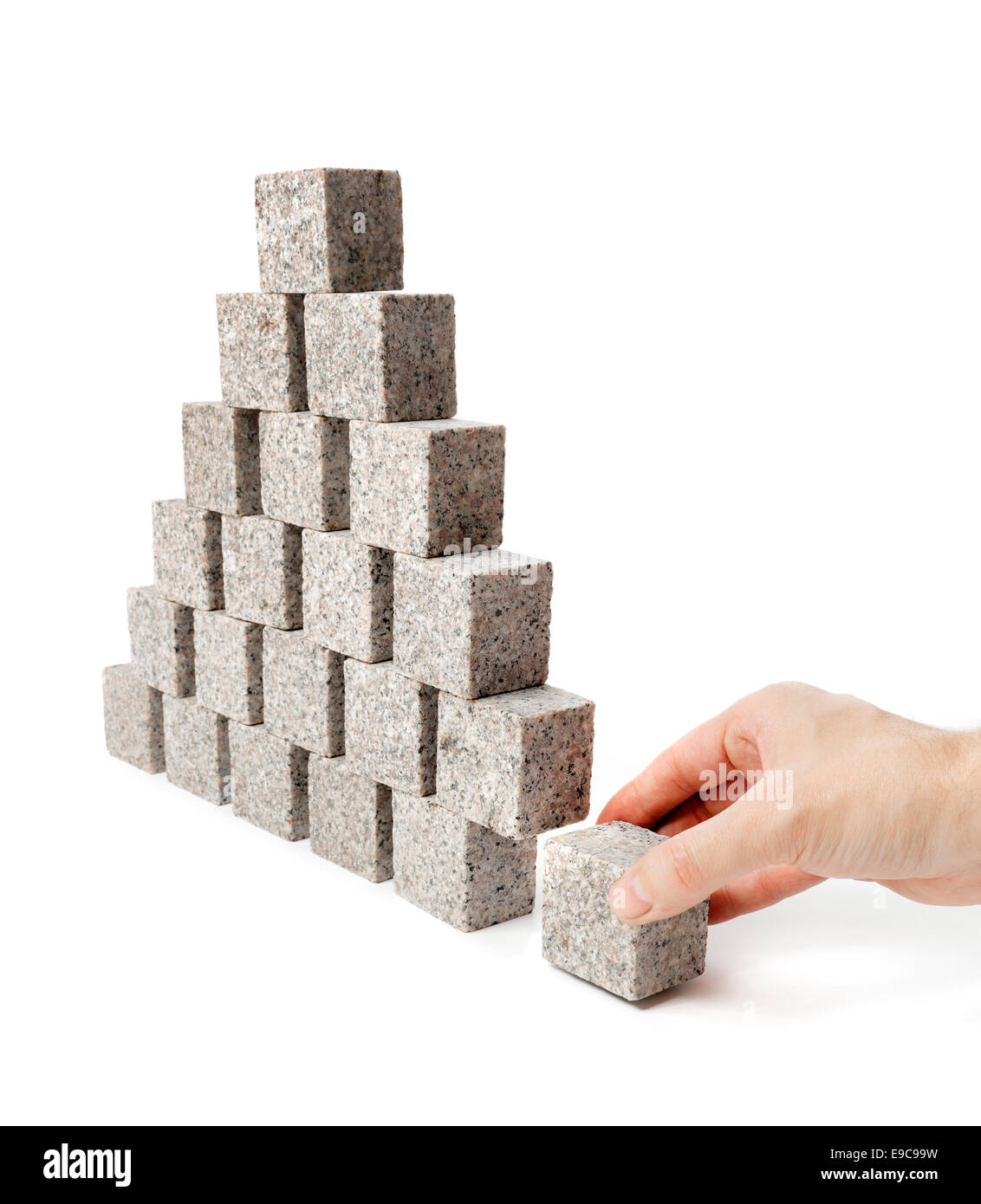 Mano che rimuove la pietra angolare di una piramide fatta di piccoli di roccia di granito blocchi. Foto Stock