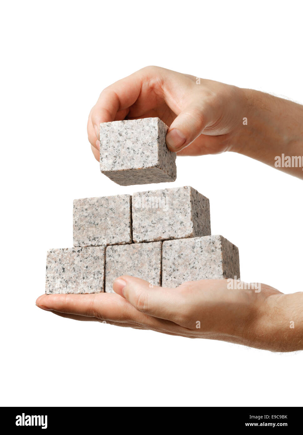 Impilatura di uomo di piccoli blocchi di roccia di granito nelle sue mani. Foto Stock