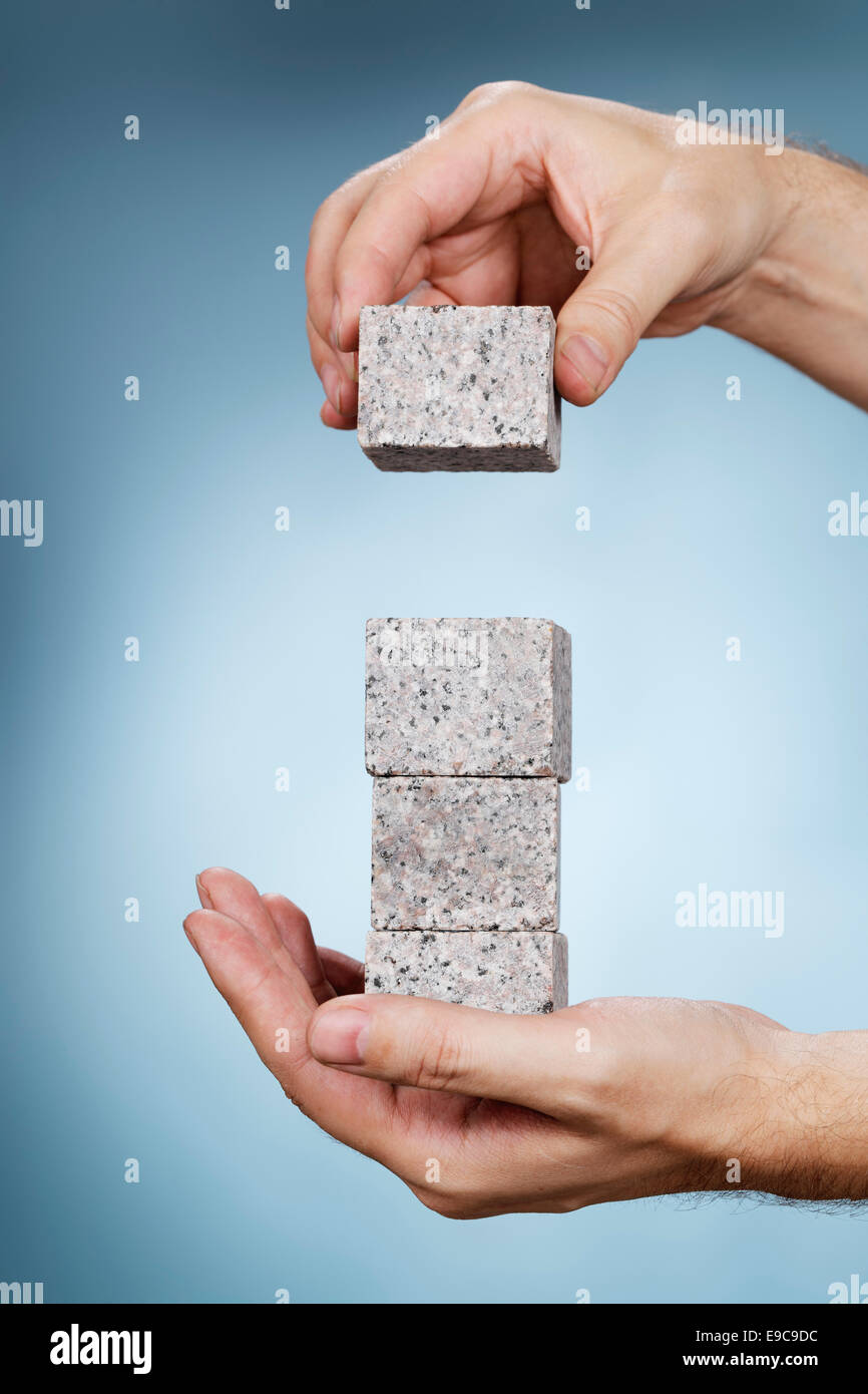 L'uomo costruire una pila di rocce di granito blocchi nelle sue mani. Foto Stock