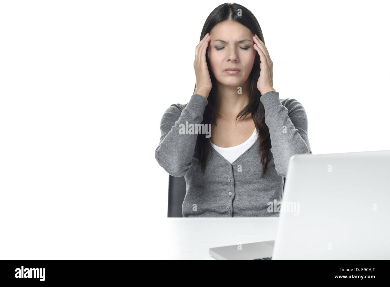 Giovane donna soffre di mal di testa o emicrania affacciata sul computer portatile sul tavolo. isolato su sfondo bianco Foto Stock