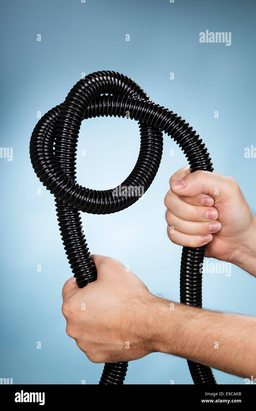 Uomo in possesso di un tubo in plastica flessibile con un nodo. Foto Stock