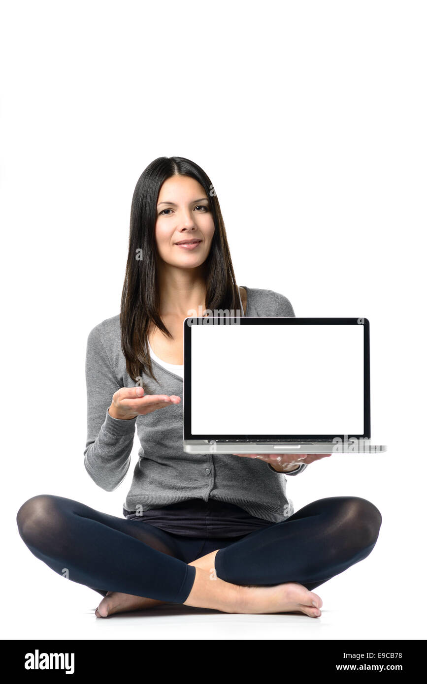 Piuttosto lunghi capelli donna meditando pone con gambe incrociate mentre di fronte a un computer portatile nella parte anteriore. Isolato su bianco Foto Stock