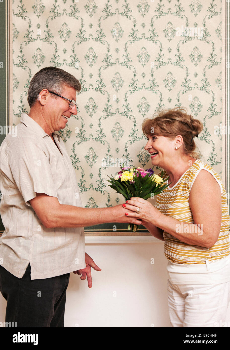 Uomo anziano dando moglie bouquet di fiori Foto Stock