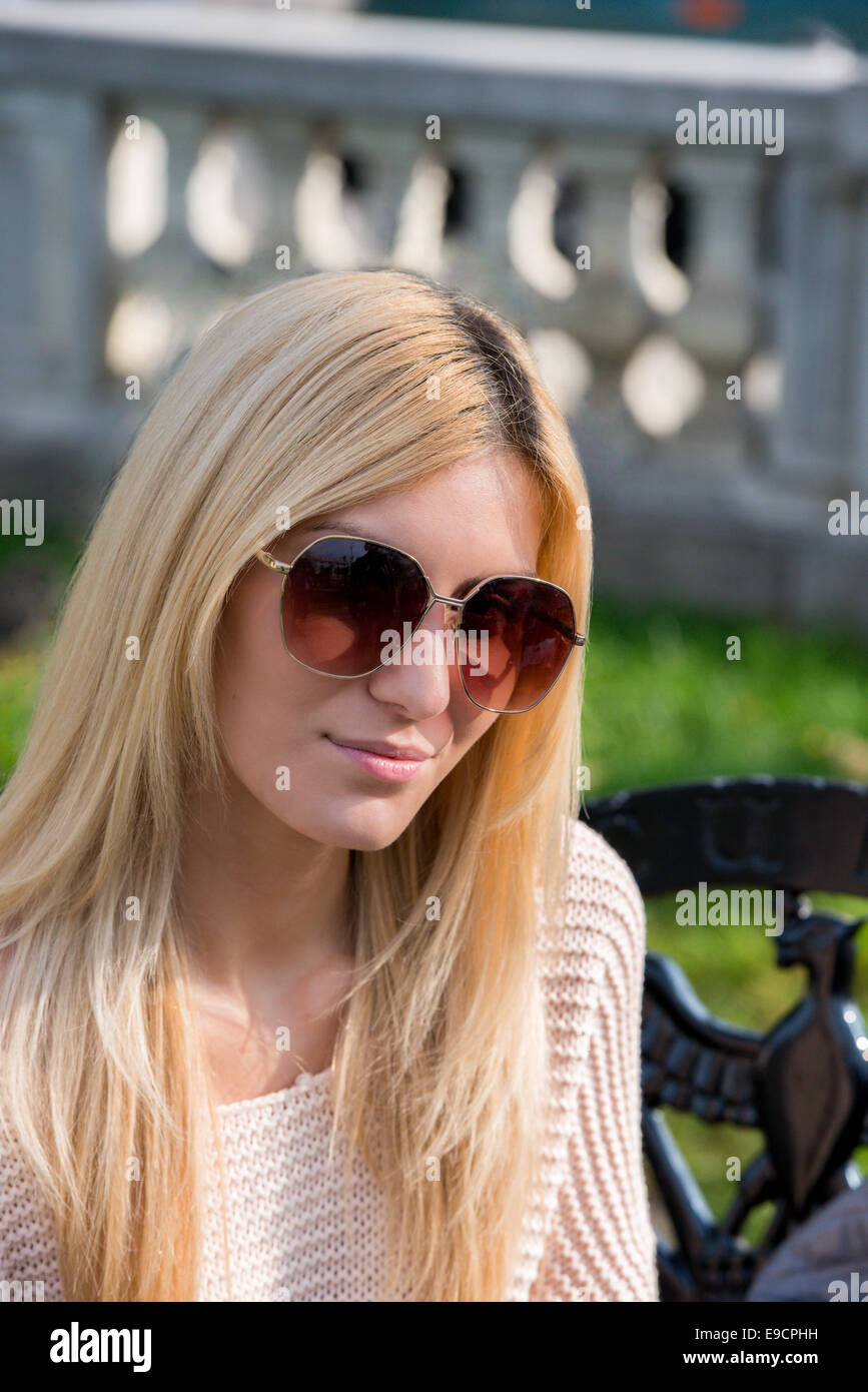 Giovane donna bionda indossando occhiali da sole nel parco Foto Stock