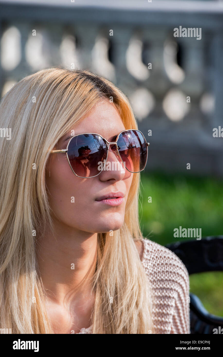 Bionda donna attraente indossando occhiali da sole nel parco Foto Stock
