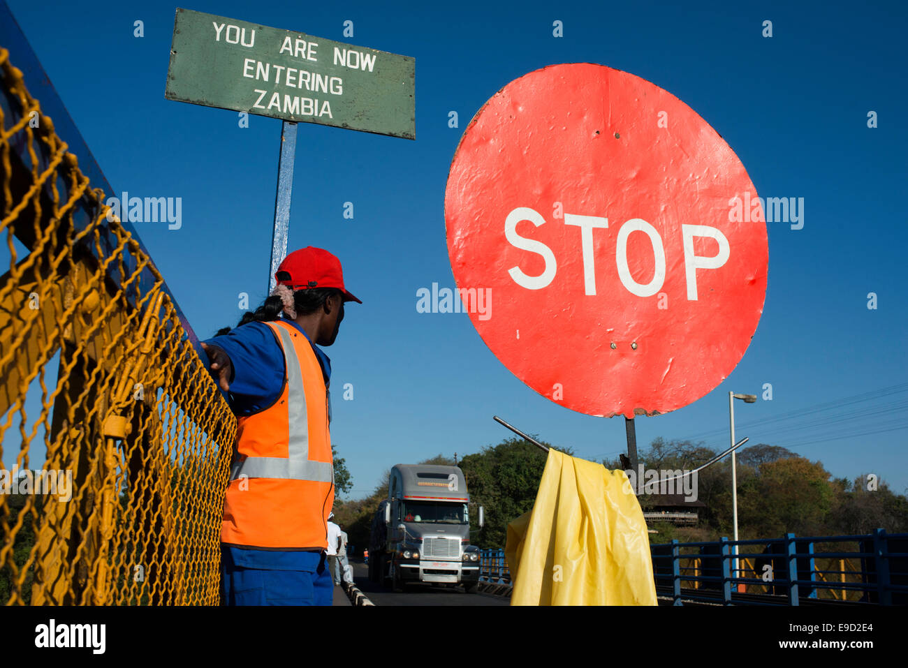 Una donna controlla il traffico tra Zambia e Zimbabwe. Un simbolo di arresto indica che stiamo entrando in Zambia. Oggi uno dei V Foto Stock