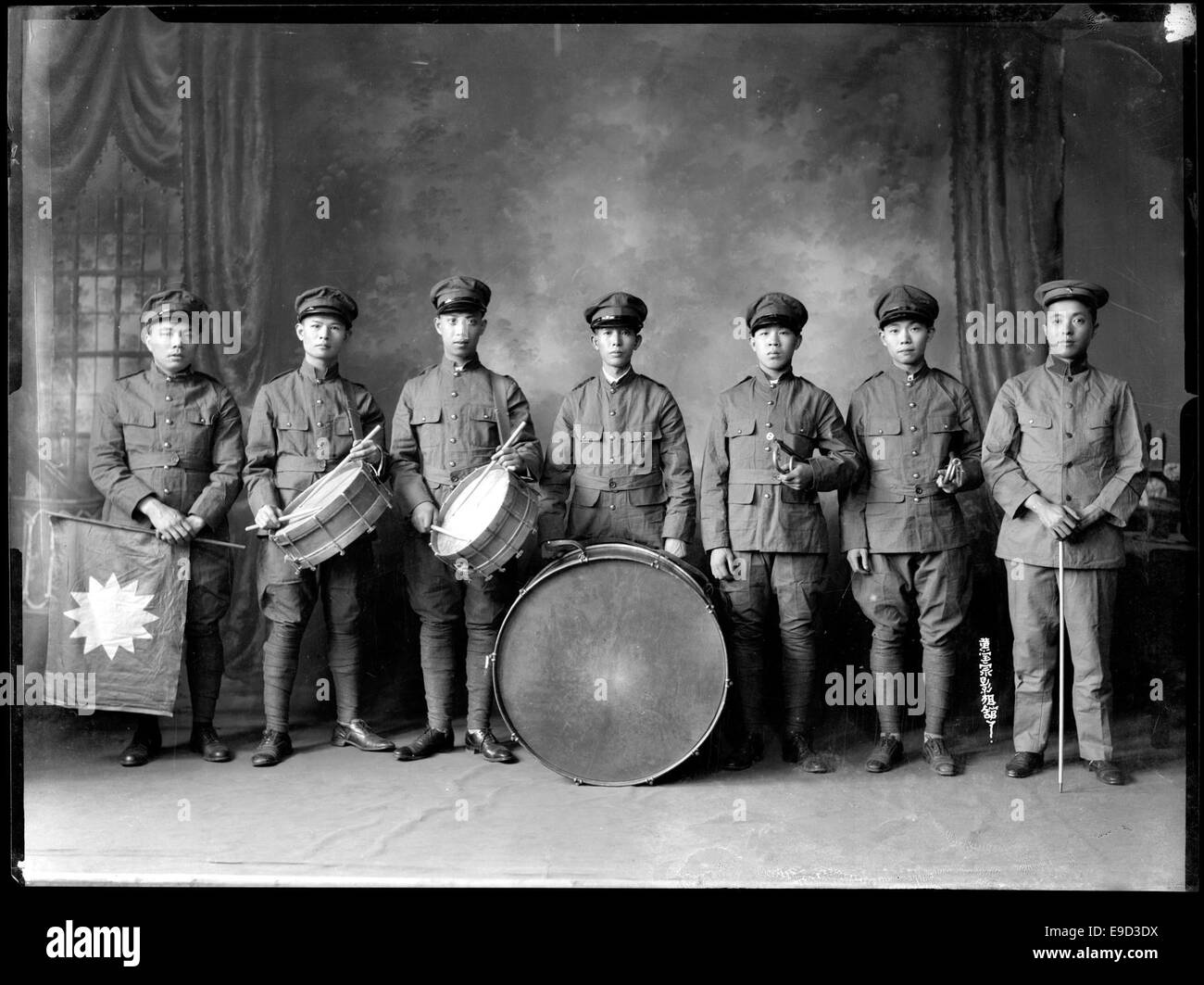 Questa fotografia cattura uomini cinesi che si esibiscono in una banda militare, probabilmente da un evento storico. L'immagine presenta i musicisti in uniforme, contribuendo alla documentazione delle tradizioni militari e culturali. Foto Stock