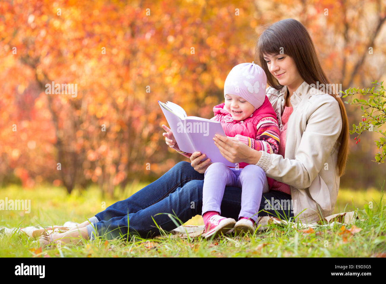La madre e il bambino a leggere un libro all'aperto in autunno Foto Stock